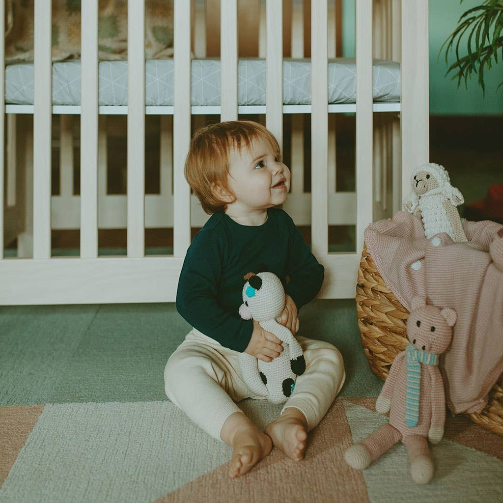 Precious Days Gifts handmade organic cotton plush cow toy with embroidered details, held by a baby.