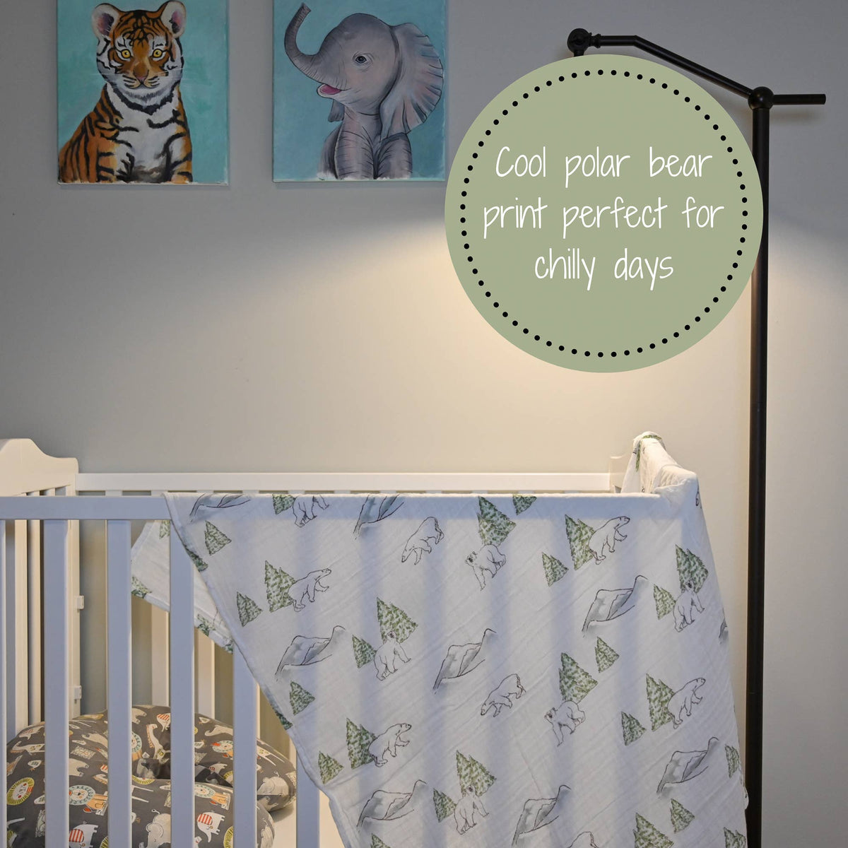 Precious Days Gifts cotton muslin swaddle blanket featuring a polar bear and pine tree print draped over a white crib