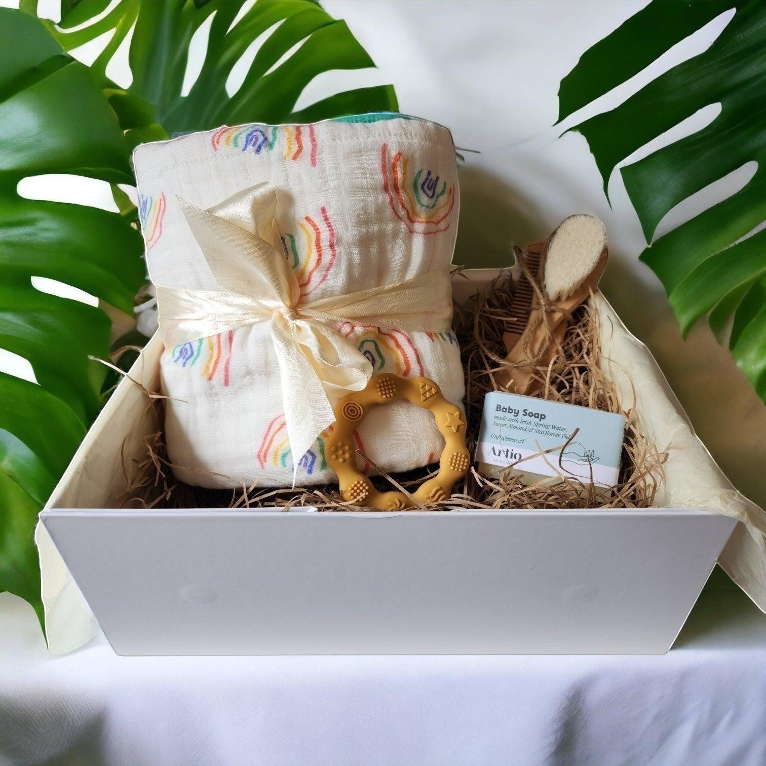 Precious Days Gifts Over the Rainbow baby gift box with 6-layer cotton muslin blanket, teether, brush, comb, and soap.