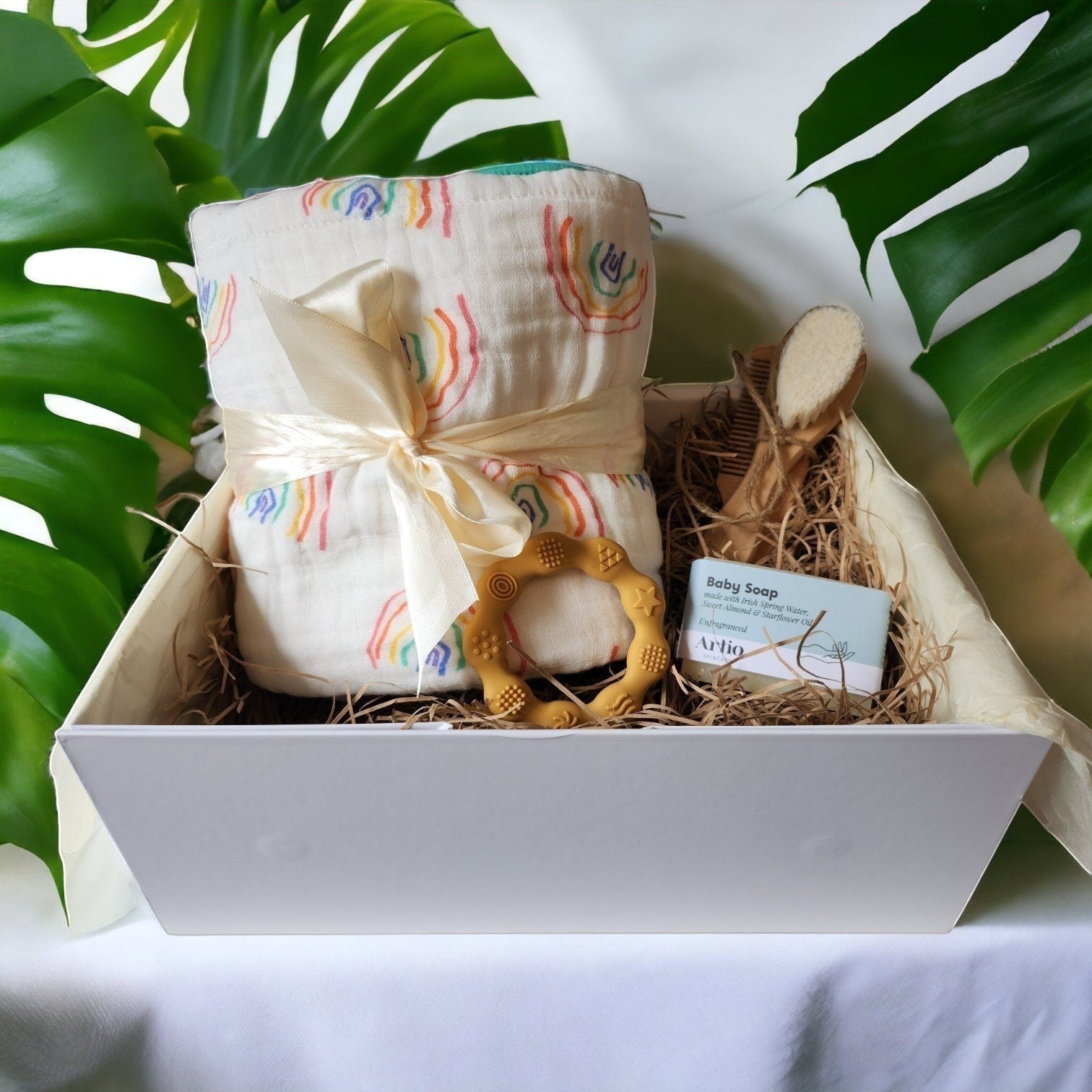 Precious Days Gifts rainbow baby hamper with muslin blanket, teether, brush, comb, and baby soap.