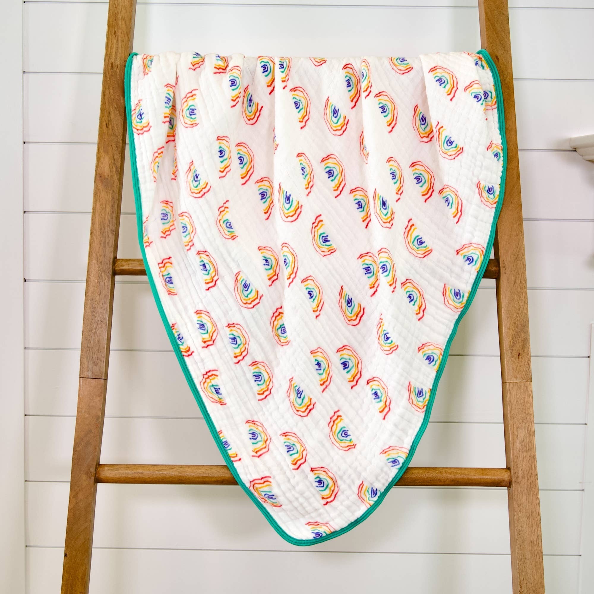Precious Days Gifts 6-layer 100% cotton muslin quilt with a hand-drawn rainbow pattern and teal trim. 120x120cm.