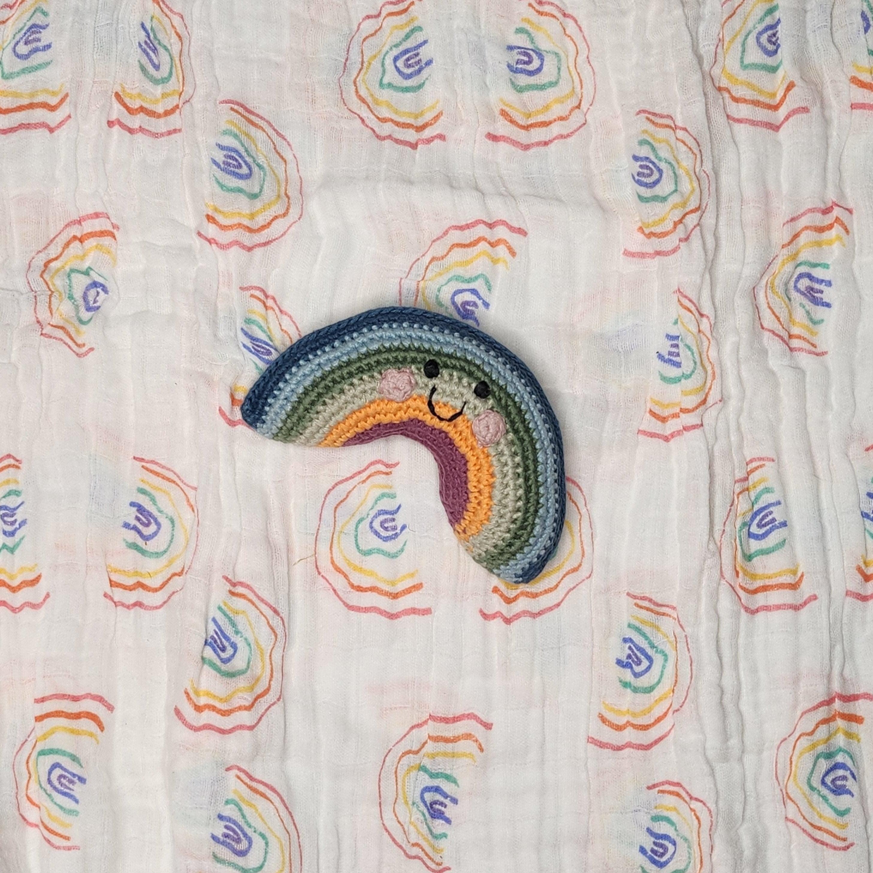 Precious Days Gifts handmade rainbow rattle with smiling face on a white cotton muslin with rainbow print.