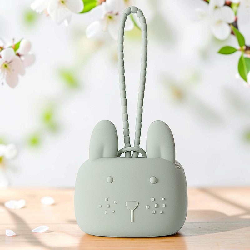 Precious Days Gifts sage green silicone bunny storage pouch with a textured wrist strap on a wooden surface.