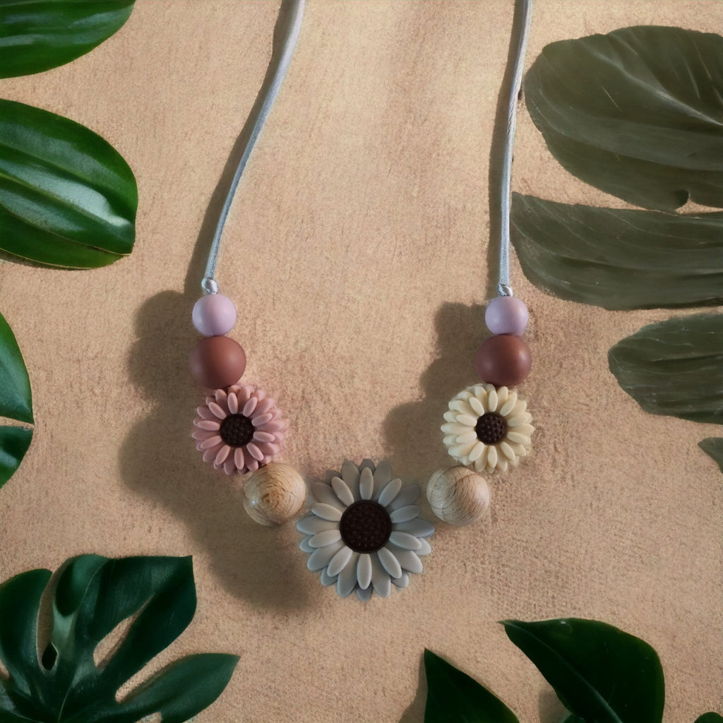 Precious Days Gifts Spring Daisy teething necklace with silicone and wood beads in pink, cream, grey, and natural wood.