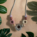 Precious Days Gifts Spring Daisy teething necklace with silicone and wood beads in pink, cream, grey, and natural wood.