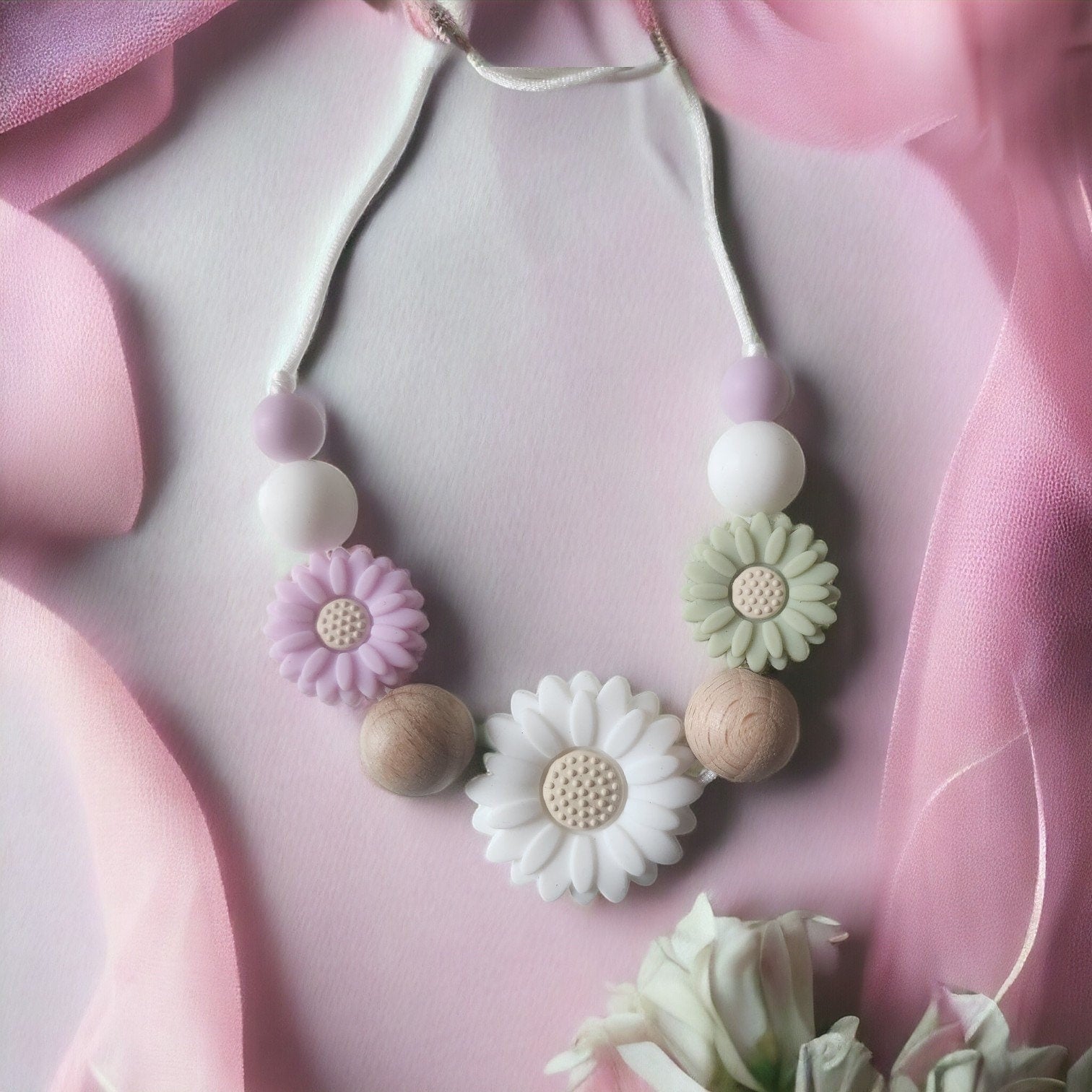 Precious Days Gifts Spring Daisy teething necklace with silicone and wood beads in pastel colors.
