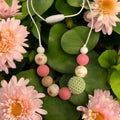 Precious Days Gifts Springtime teething necklace with pink, white, green beads and floral print. Food-grade silicone & wood.