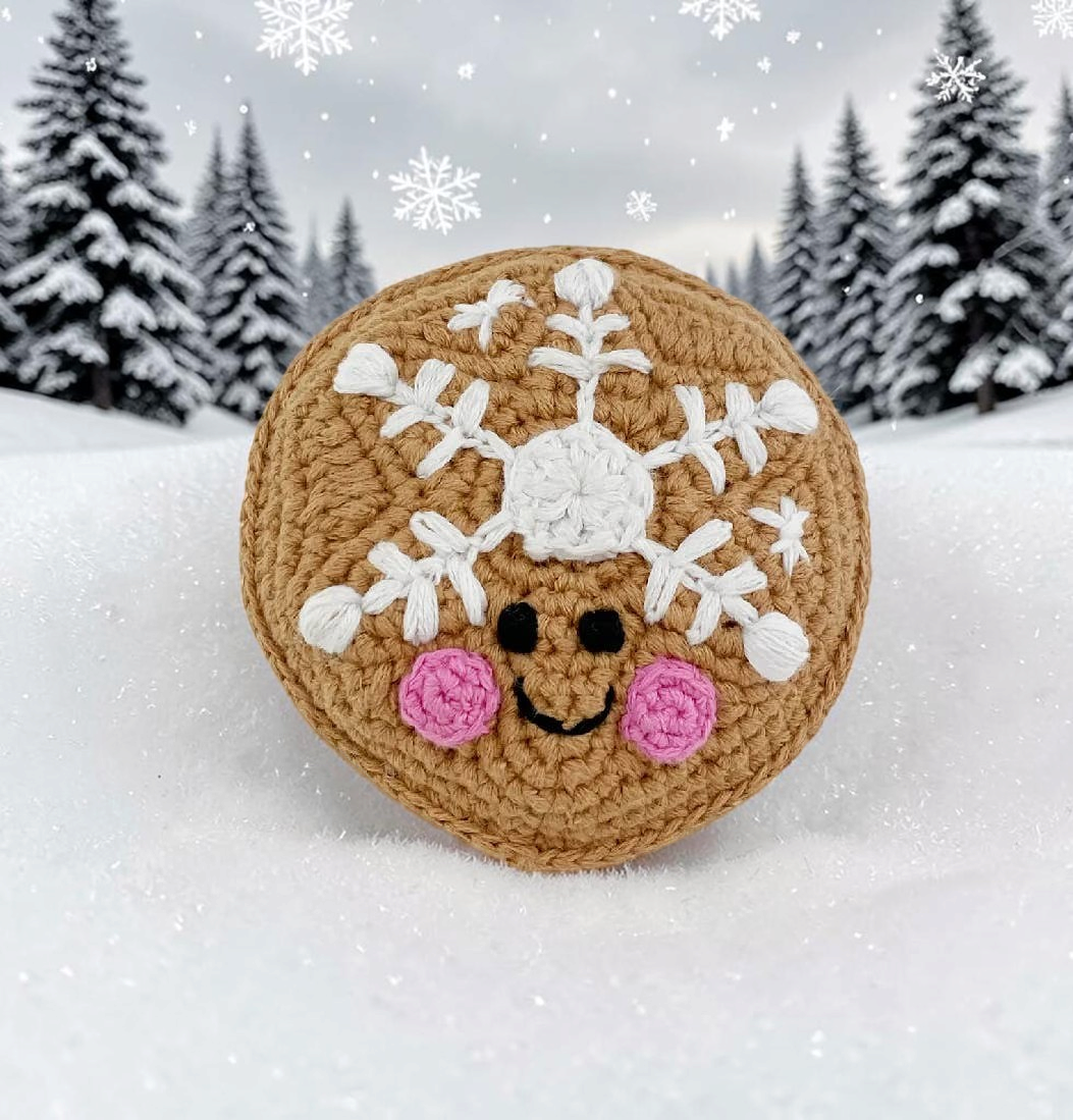 Precious Days Gifts organic cotton sugar cookie rattle with snowflake embroidery and pink cheeks in snowy setting