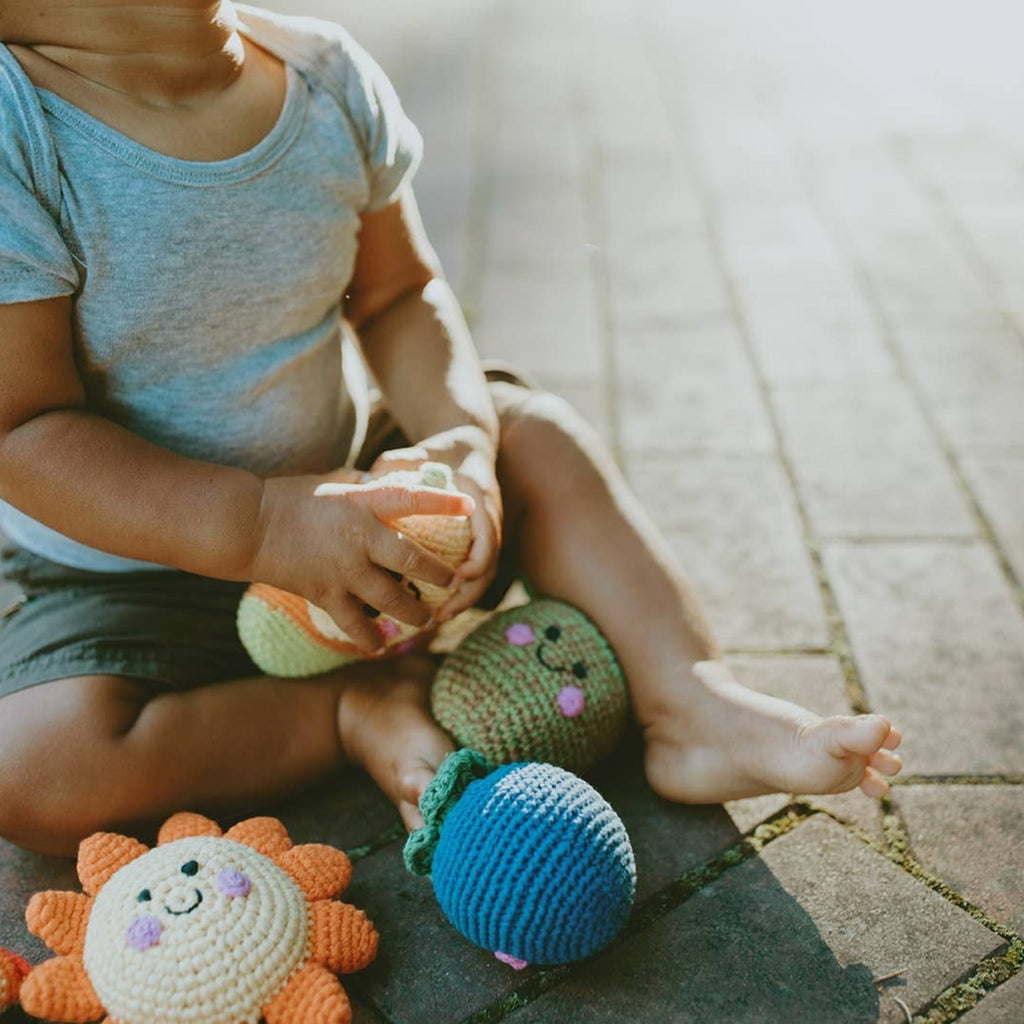 Precious Days Gifts handmade crochet sun rattle in orange and yellow with a smiling face. Soft cotton yarn, baby-friendly.