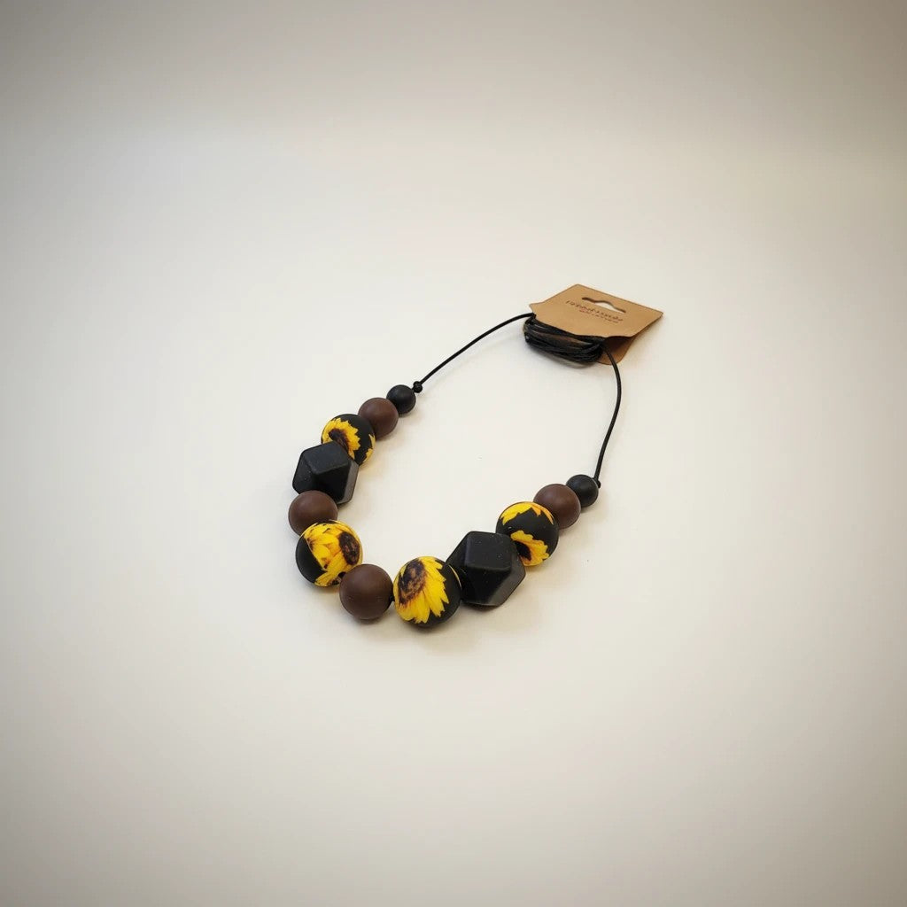 Precious Days Gifts sunflower print silicone teething necklace with brown and black beads.