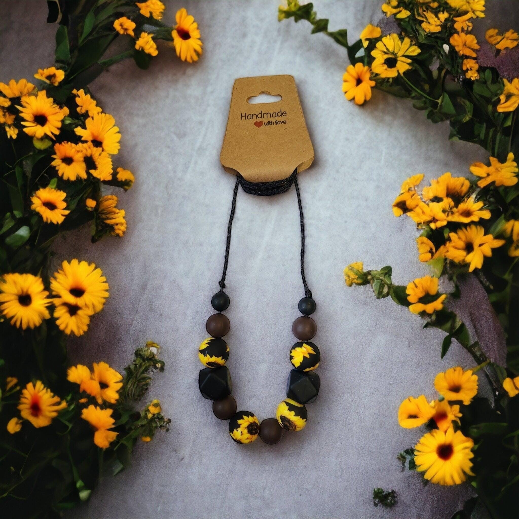 Precious Days Gifts sunflower-themed silicone teething necklace in yellow, black, and brown. BPA-free beads.