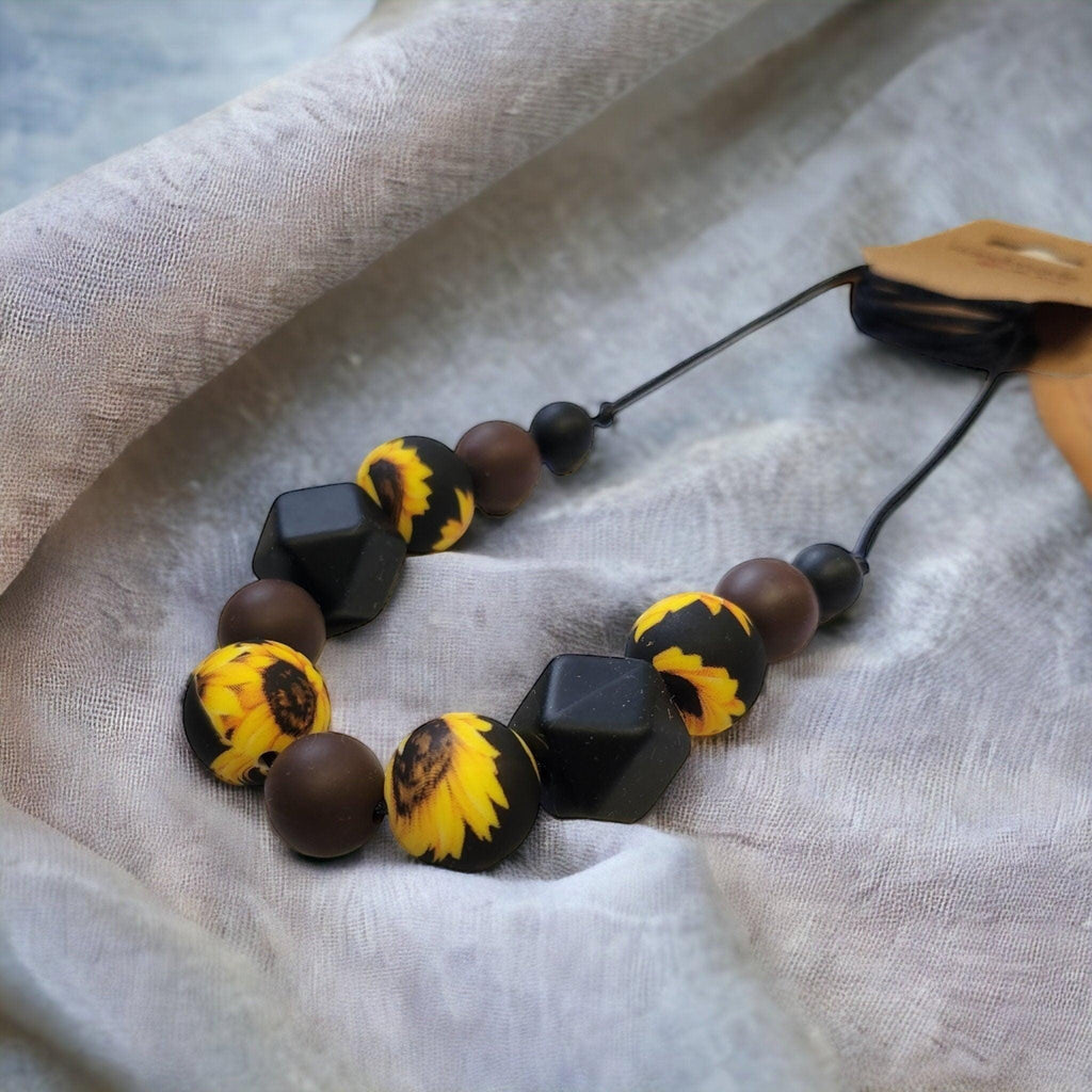 Precious Days Gifts sunflower silicone teething necklace with brown and black beads. BPA-free and food-grade.