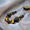 Precious Days Gifts sunflower silicone teething necklace with brown and black beads. BPA-free and food-grade.