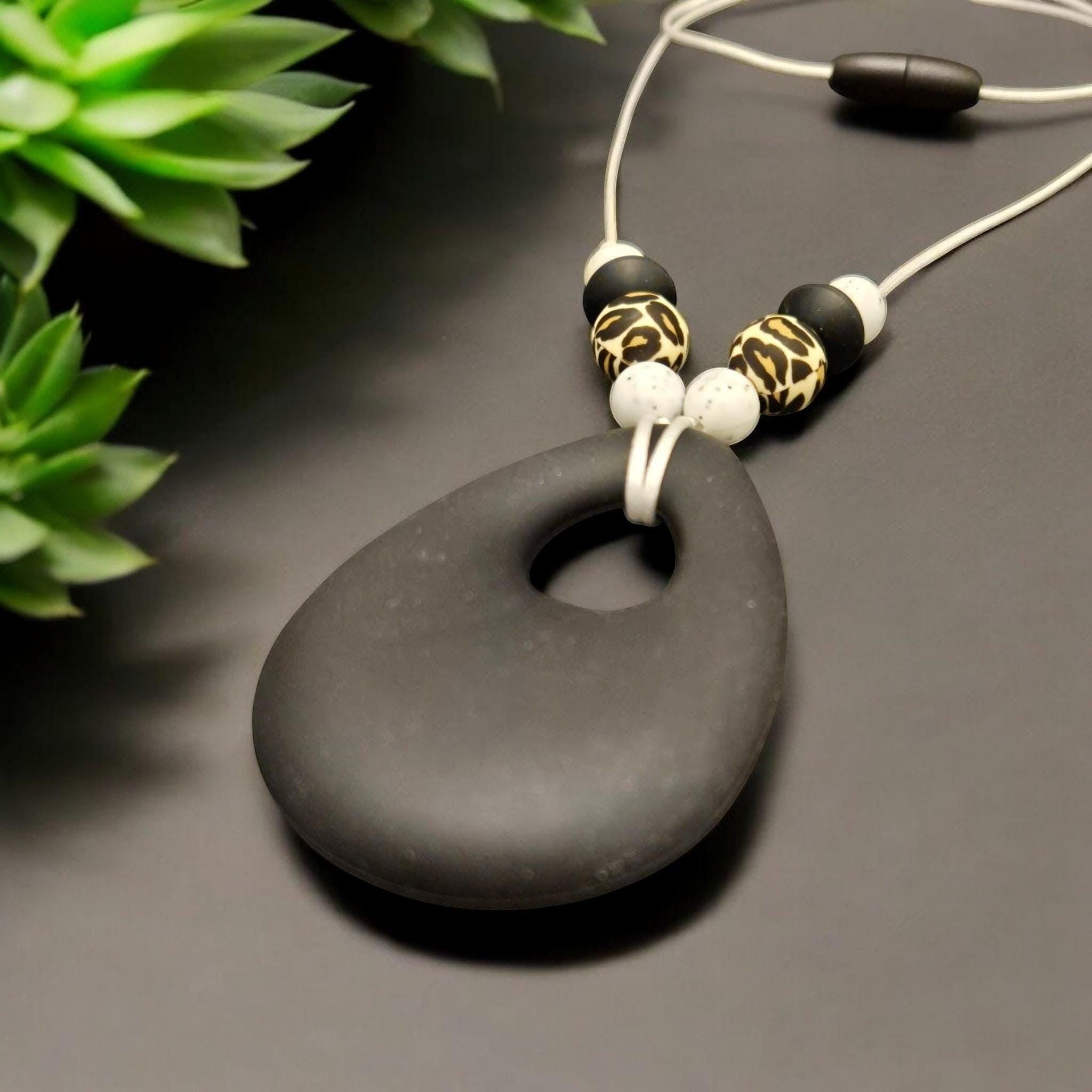 Precious Days Gifts black teardrop silicone teething necklace with leopard print and white speckled beads.