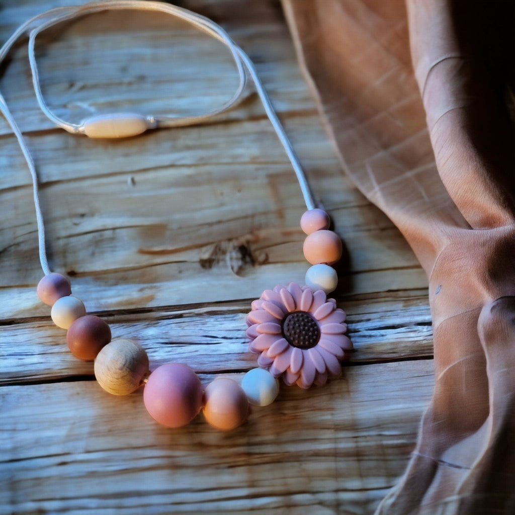Precious Days Gifts handmade teething necklace with silicone and wood beads, featuring a pink daisy pendant. Pastel colours.