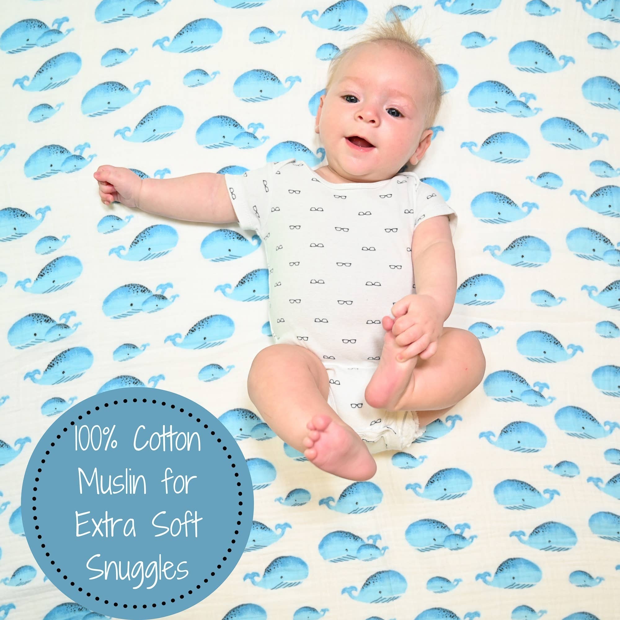 Precious Days Gifts baby swaddle blanket in 100% cotton muslin with a blue whale print. Baby wearing a white onesie with glasses print.