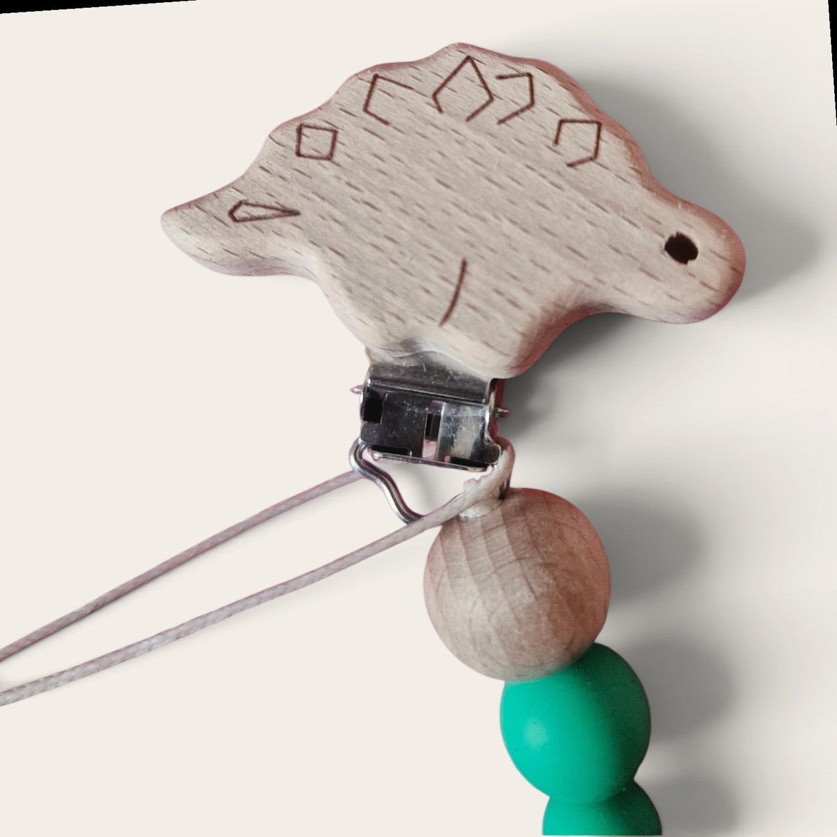 Precious Days Gifts wooden dinosaur dummy clip with green silicone and natural wooden beads on a white background